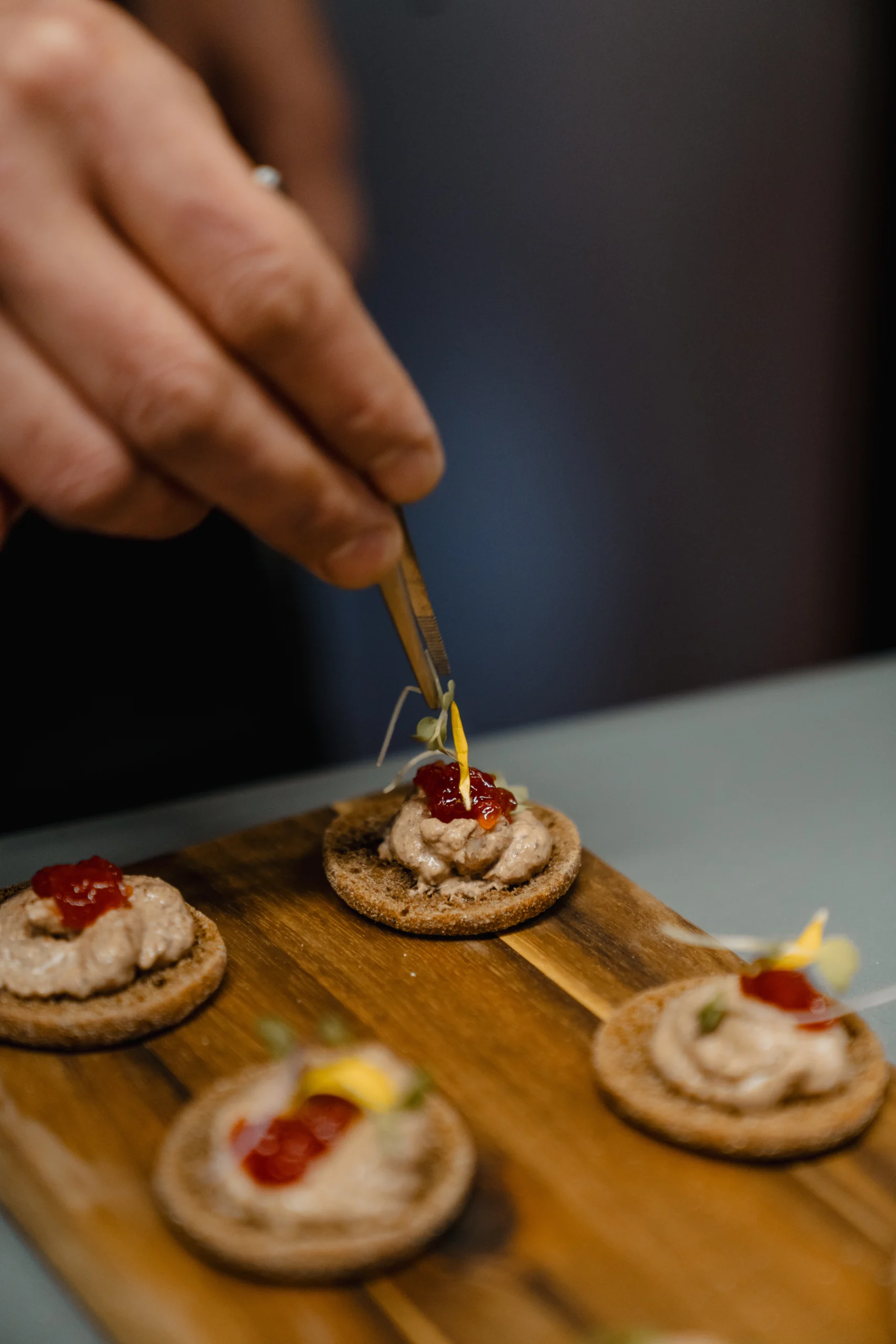 Mano de cocinero con pinzas de cocina colocando adorno en un postre de El Caserío eventos