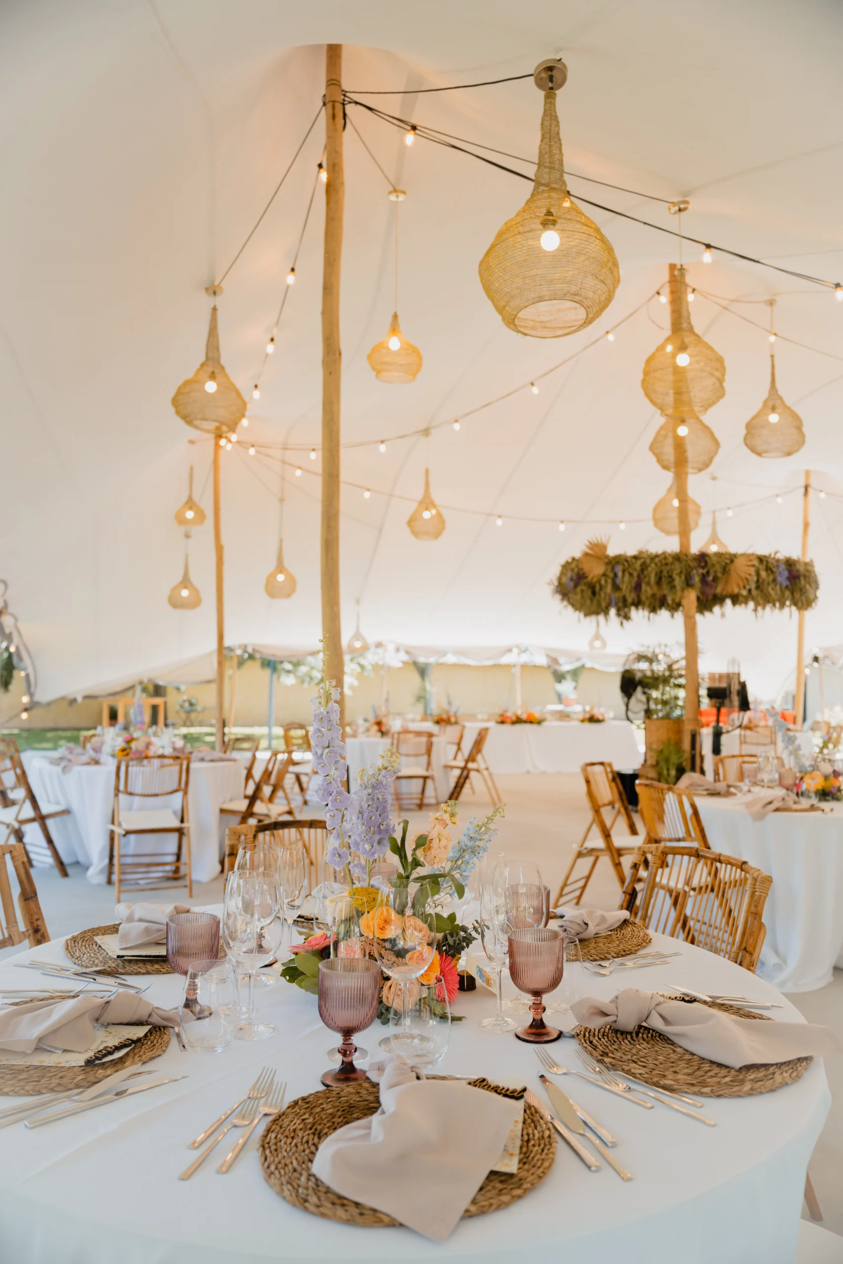 Carpa de celebraciones por dentro con lámparas colgantes y mesas decoradas para banquete de boda